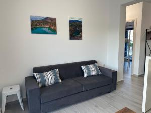 a black couch in a living room with two paintings at Kato Zaros Apartments in Zaros
