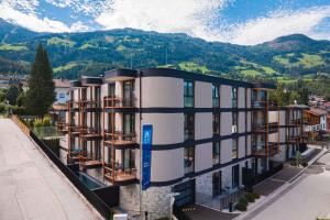 un edificio de apartamentos con balcones y montañas en el fondo en Zillertal Suites Fügen by ALPS RESORTS en Fügen