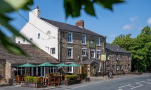 a building with tables and green umbrellas on a street at The Millstone, Mellor in Blackburn