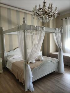 1 dormitorio con cama blanca con dosel y lámpara de araña en Al Filarmonico, en Verona