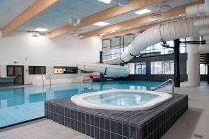 a large swimming pool with a large tub in a building at Summer House At Himmerland Golf Resort in Farsø