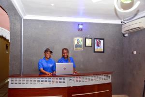 twee mensen staan aan een balie met een laptop bij BBD Hotel And Suites in Ibadan