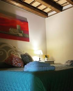 Un dormitorio con una cama azul con una pintura en la pared en Le dimore di Gió, en Trapani
