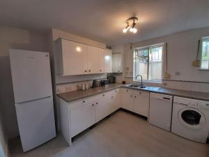 uma cozinha com um frigorífico branco e uma máquina de lavar louça em Wokingham - Central 2 beds home with parking em Wokingham
