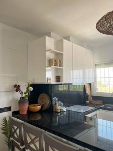 a kitchen with white cabinets and a black counter top at NIEUW: Bello Horizonte, house by the sea in Torremolinos