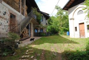 a black cat sitting in the yard of a house at Agriturismo I Sette Raggi in Ailoche +2 photos