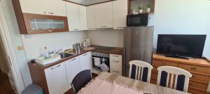 uma pequena cozinha com uma mesa e uma televisão em Apartment Riva Primošten em Primošten