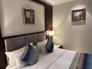 um quarto de hotel com uma cama com lençóis brancos e almofadas em Grand Palace Hotel Lusaka em Lusaka