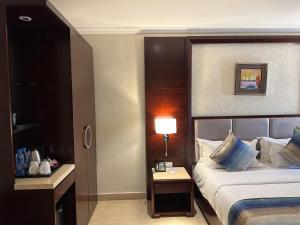 a hotel room with a bed and a table with a lamp at Grand Palace Hotel Lusaka in Lusaka