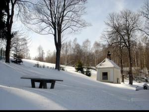 um parque coberto de neve com um banco e um edifício em Dobrá Voda u Záblatí - lesní areál 