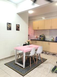 une cuisine avec une table rose et des chaises blanches dans l'établissement HOMESTAY DOABONDA, à Kajang