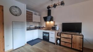 eine Küche mit einem TV und einer Uhr an der Wand in der Unterkunft Bel appartement avec piscine - Le Grand Tétras in Samoëns