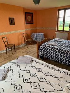 Beaubec-la-RosièreにあるChambres d'hôtesのベッド2台、テーブル、椅子が備わる客室です。
