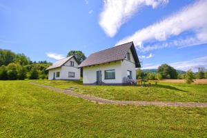 a small white house on a grassy field at Domki w Zielonym Gaju in Ustrzyki Dolne