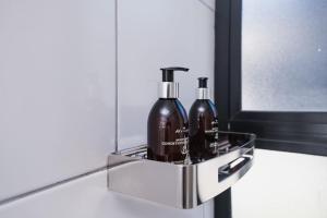 two bottles of soap in a metal holder on a bathroom counter at The Lofts Luxury Suites in Windhoek