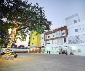 uma árvore num parque de estacionamento ao lado de um edifício em The Sky Land Hotel & Restaurant em Tuljapur