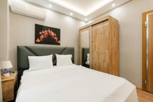 een slaapkamer met een wit bed en een houten kast bij Compact Flat 2 min to Metro, Near Marmara Park in Istanbul