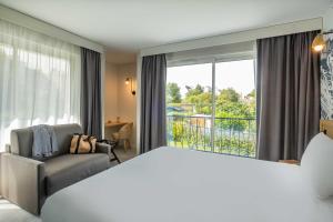 a hotel room with a large bed and a window at L'Escale Marine, The Originals Relais in Crozon