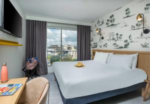 a hotel room with a large bed and a window at L'Escale Marine, The Originals Relais in Crozon