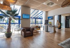 an office lobby with a palm tree and chairs at L'Escale Marine, The Originals Relais in Crozon