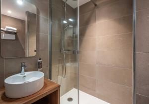 a bathroom with a sink and a glass shower at L'Escale Marine, The Originals Relais in Crozon