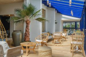 a group of chairs and tables and a palm tree at L'Escale Marine, The Originals Relais in Crozon