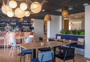 a restaurant with tables and chairs and a bar at L'Escale Marine, The Originals Relais in Crozon