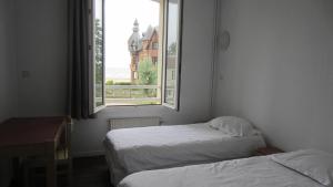 Cette petite chambre comprend 2 lits et une fenêtre. dans l'établissement Centre de Vacances CPCV Normandie à 50 metres de la plage de Houlgate, à Houlgate