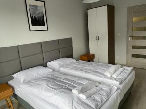 uma cama com lençóis brancos e almofadas em Apartamenty Delux-S1 przy trasie S1 em Łodygowice