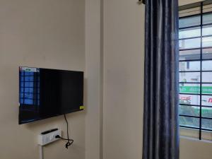 TV de pantalla plana en una pared junto a una ventana en Happy holiday Inn en Chikmagalūr