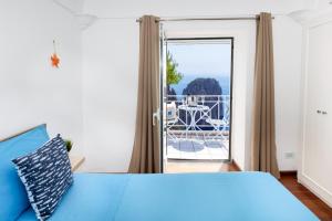 a bedroom with a blue bed and a balcony at Faraglionensis MonaconeHouse Villa in Capri