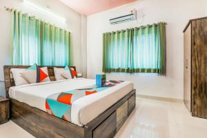 1 dormitorio con 1 cama grande y cortinas verdes en FabExpress Diamond Residency, en Pune