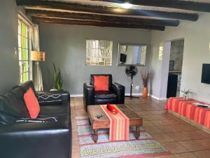 a living room with black leather furniture and a table at Sabie Self Catering Apartments in Sabie