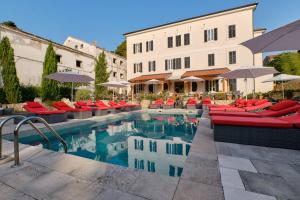 ヴェリ・ロシニュにあるDolphin Suitesの赤い椅子とパラソル付きのプールを併設するホテルです。
