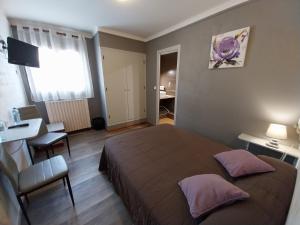 Hôtel L'Oustalet في فون-رومو-أوديللو-فيا: غرفة نوم بسرير وطاولة ومكتب