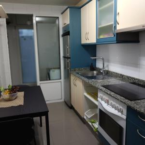- une cuisine avec des placards bleus, un évier et une table dans l'établissement Recanto Milladoiro, à O Milladoiro
