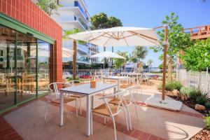 萨洛Terra Aurea Aparthotel的庭院内桌椅和遮阳伞
