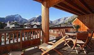une terrasse en bois avec une table et des chaises. dans l'établissement Vacancéole - Résidence Cortina, à Les Deux Alpes