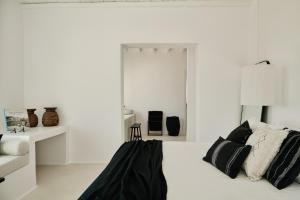 a white bedroom with a bed with black and white pillows at Villa La Piscine Mykonos in Houlakia