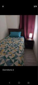 a bedroom with a bed with a blue pillow and a table at Habitaciones en Departamento Centro de Chillan in Chillán
