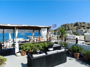a patio with chairs and plants and a view of the ocean at Odyssey Hotel Apartments in Karpathos Town