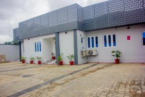 a white building with potted plants in front of it at Thistle Greens Apartment in Ikeja