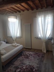 a bedroom with a bed and two windows and a rug at Monolocale Lucca PellegriniLittleHouse in Lucca