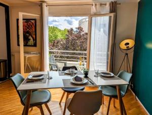 een eetkamer met een tafel en stoelen en een groot raam bij Séjour en famille ou amis à Disneyland & Paris in Lognes