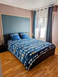 een slaapkamer met een bed met een blauw dekbed en een raam bij Séjour en famille ou amis à Disneyland & Paris in Lognes