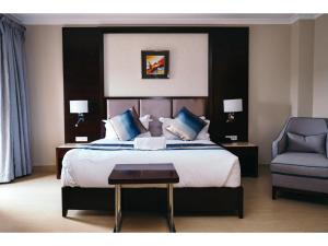 a bedroom with a large bed and a chair at Grand Palace Hotel Lusaka in Lusaka