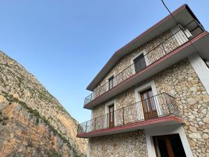 a building with balconies next to a stone wall at L'oasi del raganello in Civita