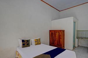 a bedroom with a bed and a wooden cabinet at SPOT ON 92906 Surya Indah Homestay Syariah in Mojokerto