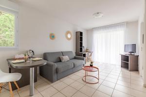 a living room with a couch and a table at Appart'City Classic Toulouse Tournefeuille in Tournefeuille