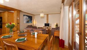 comedor y sala de estar con mesa de madera en Vacancéole - Résidence Cortina, en Les Deux Alpes